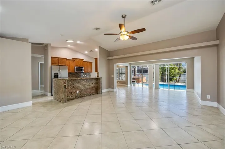 Living room with a ceiling fan, lofted ceiling, light tile patterned floors, and recessed lighting