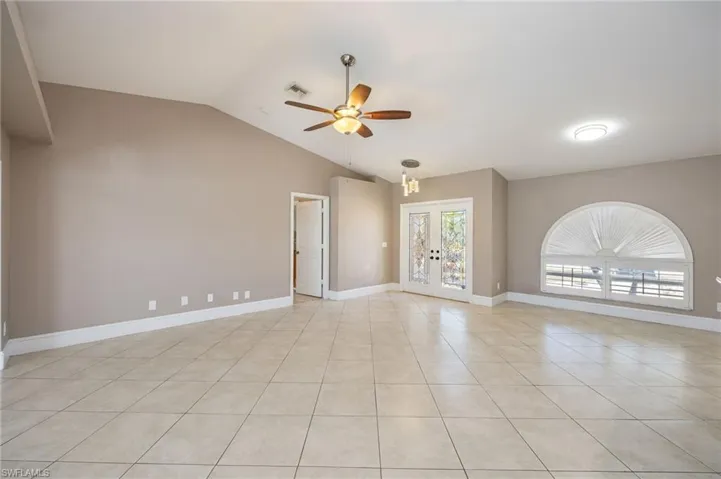 Living room with french doors, vaulted ceiling, ceiling fan, and light tile patterned floors