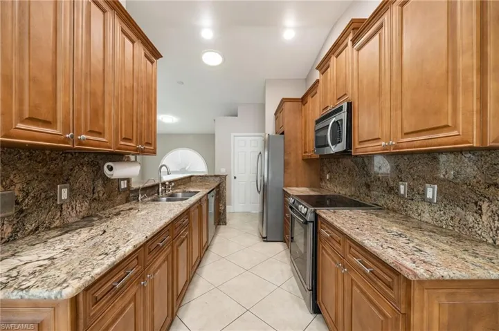 Kitchen featuring wood finish cabinets, stainless steel appliances, and light stone counters