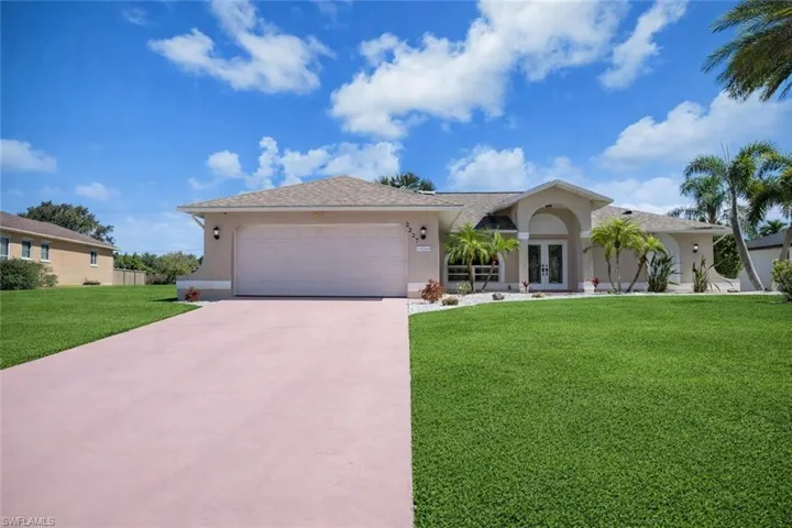 Ranch-style home featuring french doors, stucco siding, a front lawn, and driveway