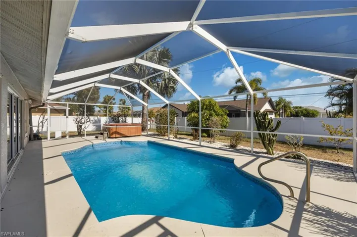 View of swimming pool with patio surround, a hot tub, a fenced backyard, and screen enclosure