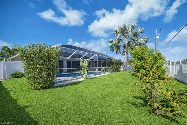 Fenced backyard featuring a lanai, an outdoor pool, and fruit trees