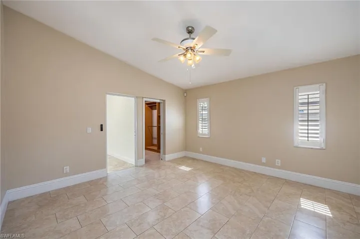 Primary bedroom with lofted ceiling and a ceiling fan