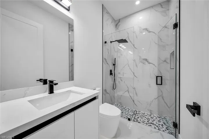 Bathroom featuring vanity, toilet, and an enclosed shower