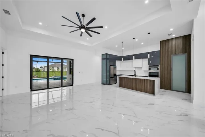 Kitchen with a kitchen island with sink, pendant lighting, a raised ceiling, and ceiling fan