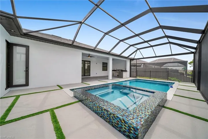 View of pool featuring glass enclosure, ceiling fan, a patio, and an in ground hot tub