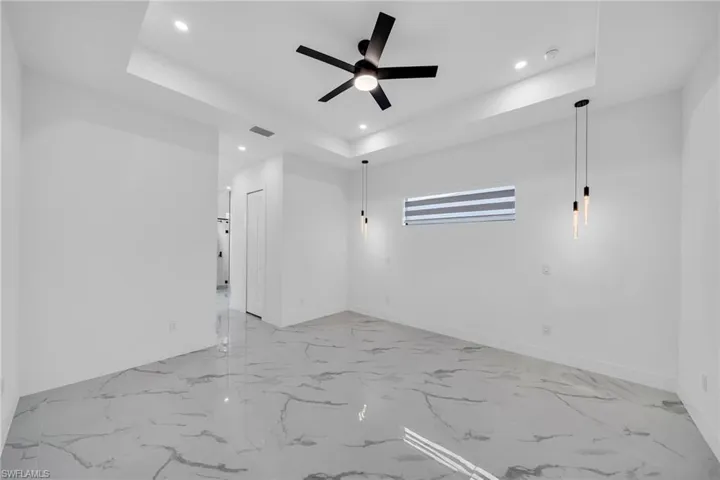 Unfurnished room featuring ceiling fan and a raised ceiling