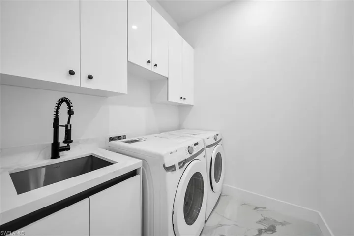 Laundry room with washer and dryer, cabinets, and sink