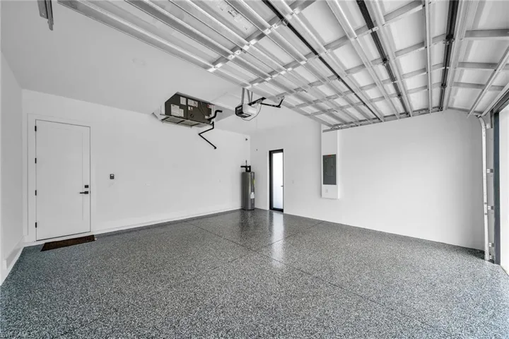 Garage with a garage door opener, electric panel, and water heater