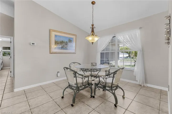 Dining room with vaulted ceiling, light tile patterned floors, and baseboards