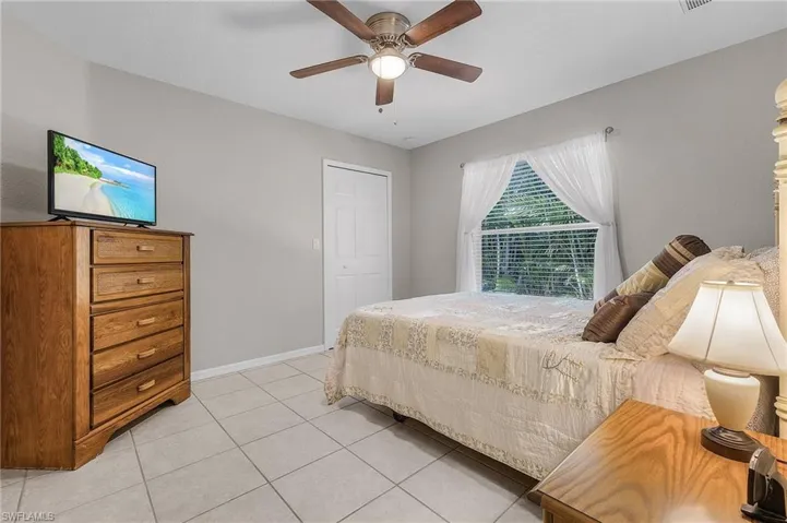 Bedroom with light tile patterned floors, a closet, baseboards, and ceiling fan