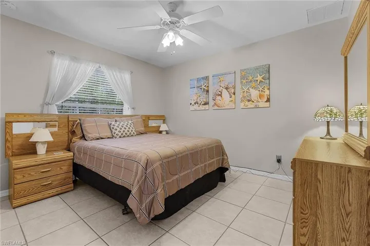 Bedroom with light tile patterned floors, a ceiling fan, and visible vents