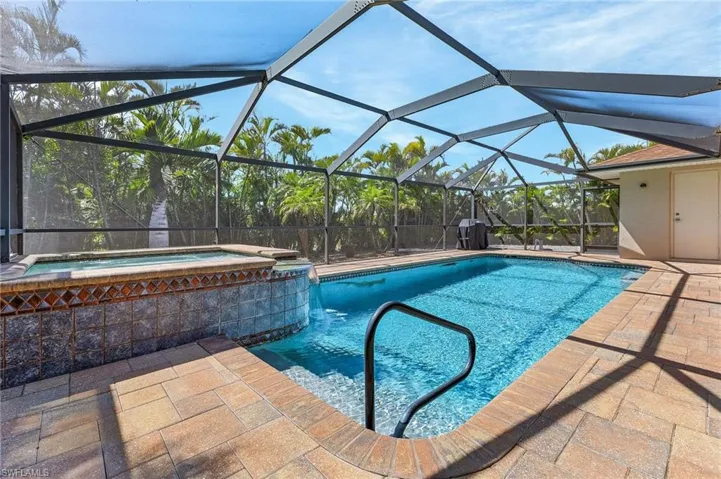 View of pool featuring glass enclosure, a patio, and a pool with connected hot tub