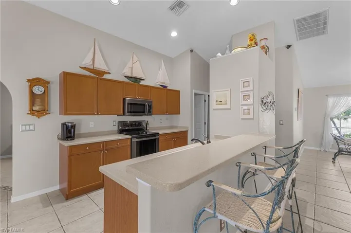 Kitchen with visible vents, arched walkways, appliances with stainless steel finishes, and light countertops