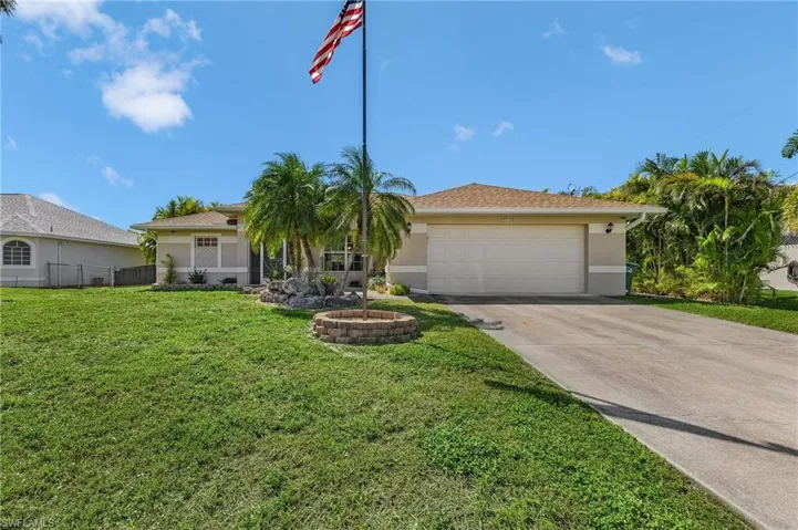 View of front of property featuring stucco siding, a front lawn, fence, concrete driveway, and a garage