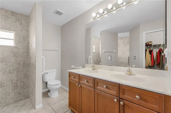 Full bath featuring tile patterned floors, double vanity, visible vents, and a sink