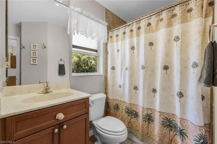 Full bath featuring a shower with shower curtain, toilet, and vanity