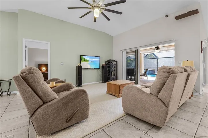 Living room featuring a ceiling fan, baseboards, a sunroom, and high vaulted ceiling