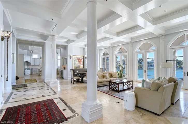 Living room featuring coffered ceiling, french doors, a water view, crown molding, and beam ceiling