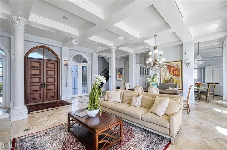 Living room with beam ceiling, ornate columns, and an inviting chandelier
