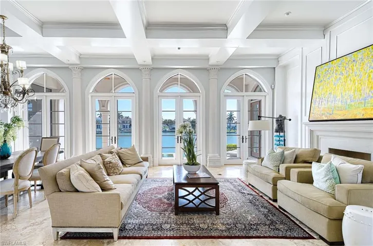 Living room with a notable chandelier, beam ceiling, a water view, and coffered ceiling