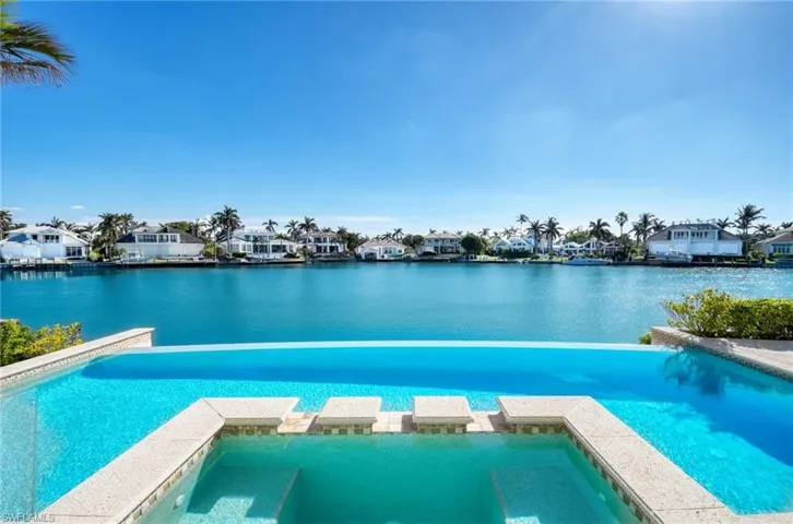 View of swimming pool with an in ground hot tub and a water view