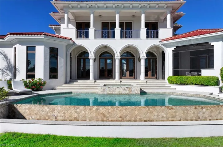 Rear view of house with a swimming pool with hot tub, a balcony, and french doors
