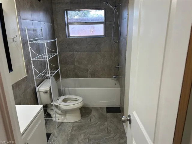 Bathroom with toilet, shower / washtub combination, and vanity
