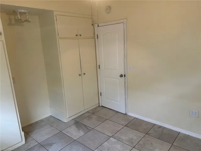 Unfurnished bedroom with baseboards, light tile patterned floors, and a closet