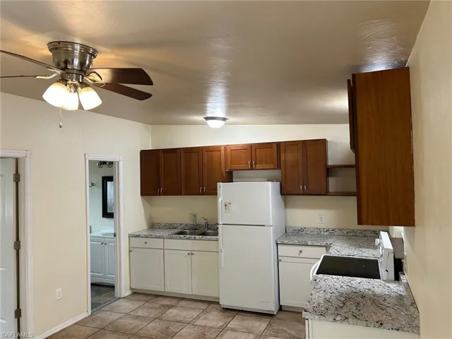 Kitchen featuring white appliances, a sink, open shelves, a ceiling fan, and light tile patterned floors