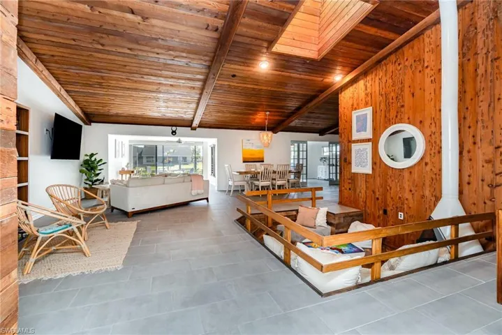 Tiled living room with wood ceiling, plenty of natural light, vaulted ceiling with wooden beams