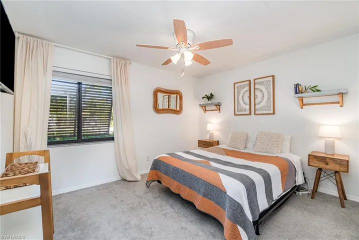 Carpeted second bedroom featuring a large closet with organizers and a ceiling fan