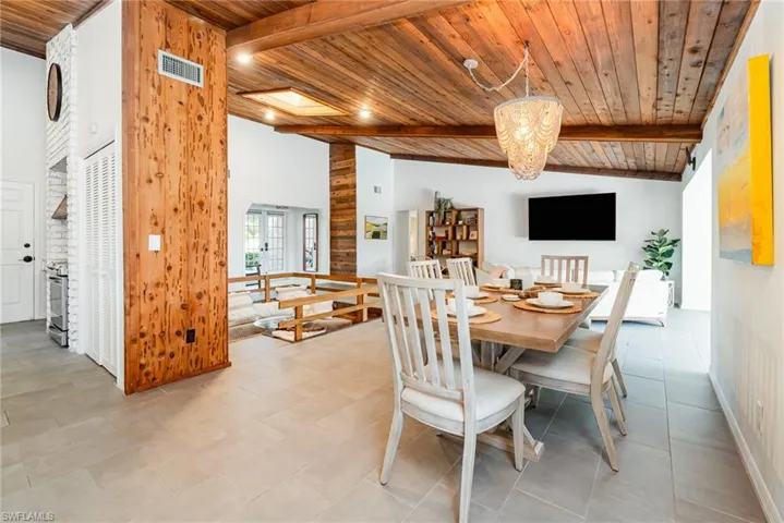 Dining room with tile flooring, wood ceiling, a chandelier, lofted ceiling with wooden beams