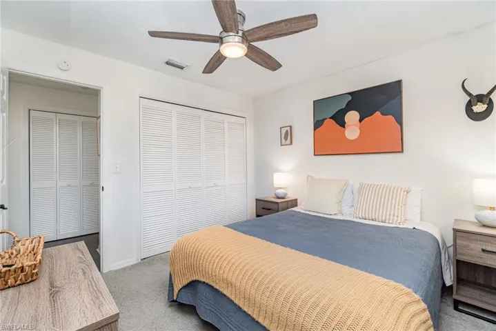 Carpeted third bedroom featuring a large closet with organizers and a ceiling fan