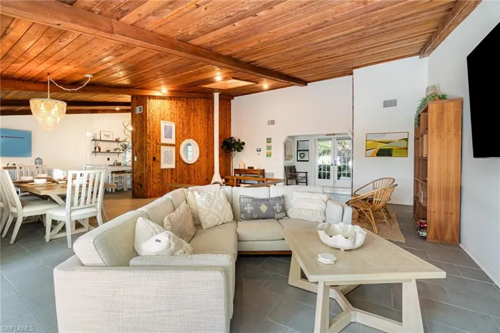 Tiled living room with wood ceiling, plenty of natural light, vaulted ceiling with wooden beams