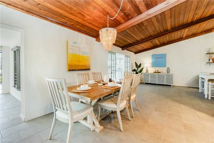 Dining room with tile flooring, wood ceiling, a chandelier, lofted ceiling with wooden beams