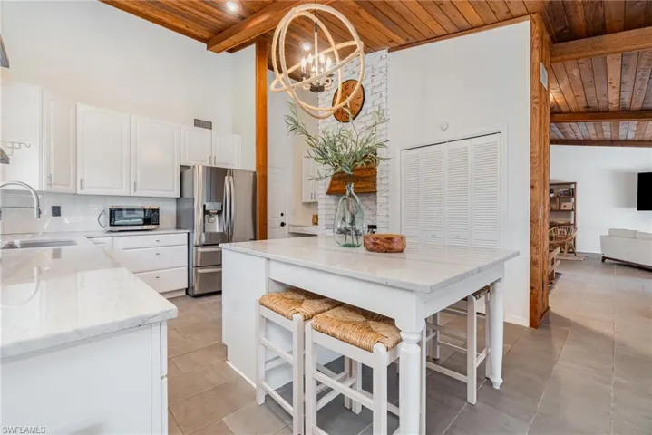 Kitchen featuring wooden ceiling, open shelves, tasteful backsplash, stainless steel appliances, and white cabinets
