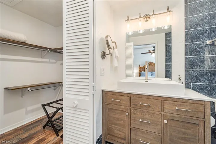 Master bathroom featuring wood vanity, and a spacious walk-in closet