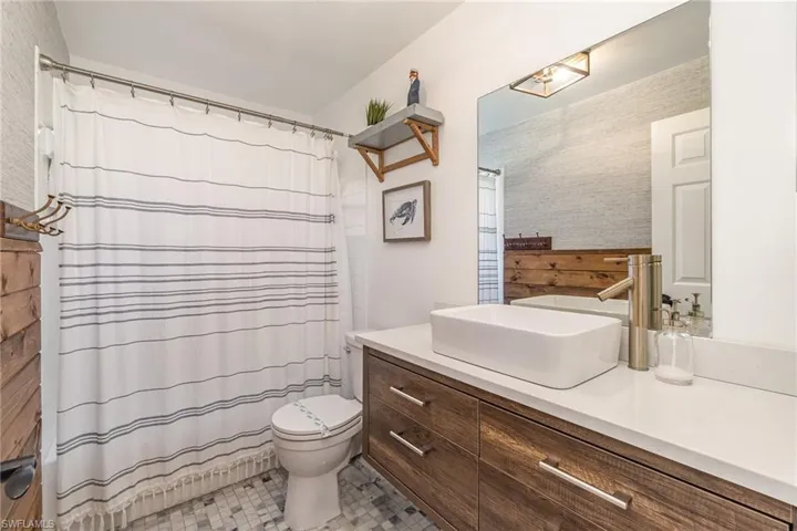 Second full bathroom with a shower, tub, tile flooring, and wooden vanity