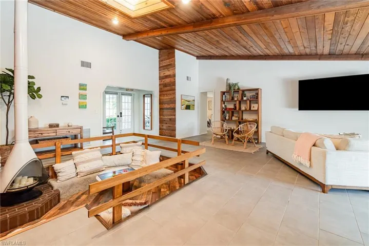 Tiled living room with wood ceiling, plenty of natural light, vaulted ceiling with wooden beams