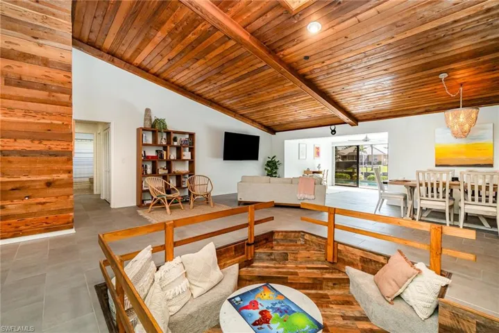 Tiled living room with wood ceiling, plenty of natural light, vaulted ceiling with wooden beams