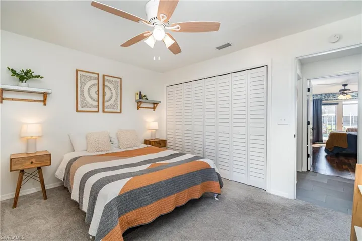 Carpeted second bedroom featuring a large closet with organizers and a ceiling fan