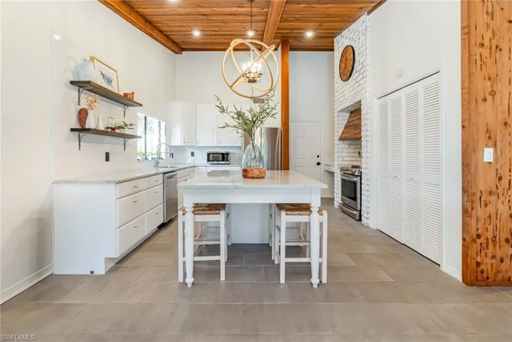 Kitchen featuring wooden ceiling, open shelves, tasteful backsplash, stainless steel appliances, and white cabinets