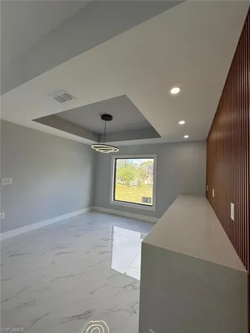 Unfurnished dining area featuring wooden walls and a tray ceiling
