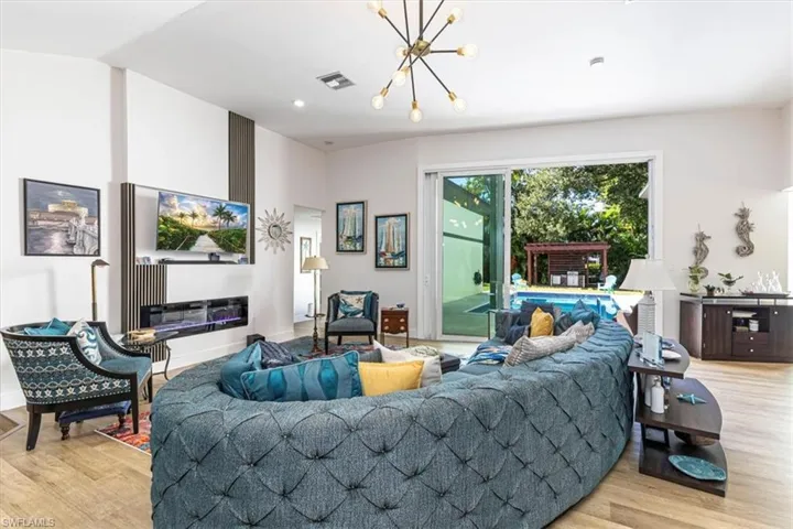 Living room with light wood-style floors, a chandelier, and recessed lighting