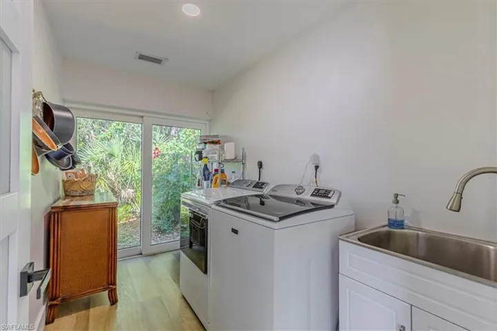 Washroom with light wood-type flooring, washer and dryer, and recessed lighting
