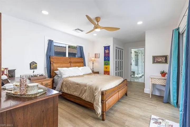 Bedroom with light wood-style flooring, ceiling fan, recessed lighting, and ensuite bathroom