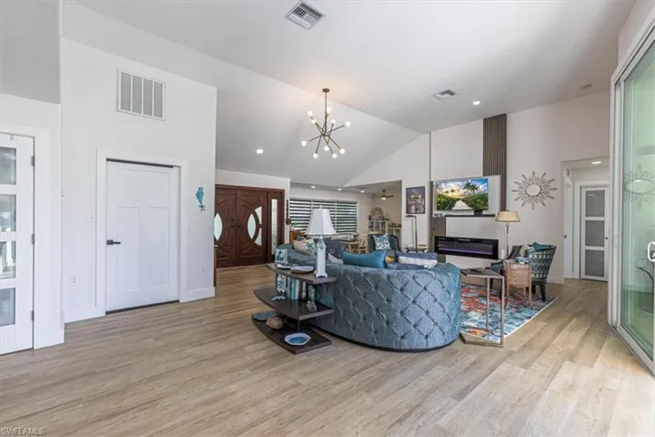 Living area with a chandelier, light wood finished floors, a ceiling fan, recessed lighting, and high vaulted ceiling