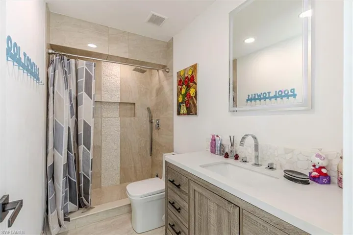 Bathroom featuring walk in shower, vanity, and recessed lighting