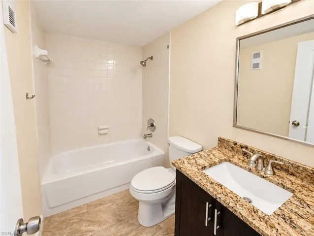 Bathroom featuring a single vanity with stone countertop, undermount sink, dark wood-finish cabinetry, and chrome fixtures